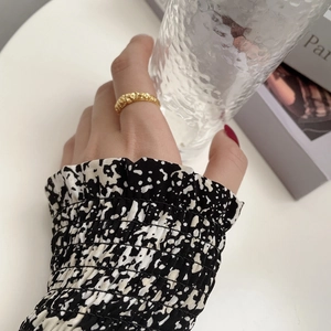 Detailed view of gold irregular lava texture ring styled with elegant floral sleeve