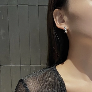 Close-up of minimalist S925 sterling silver twisted croissant hoop earring on model ear