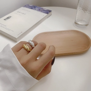 Detail of gold and silver twisted weave rings worn on fingers in a lifestyle setting