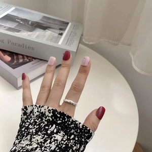 Detail of silver textured ring paired with burgundy and pink checkered press-on nails