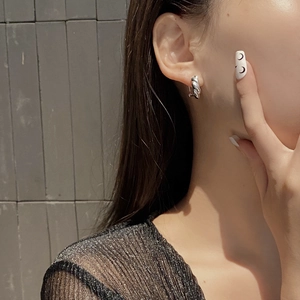 Close-up of S925 sterling silver twist hoop earrings on a model with geometric wave design