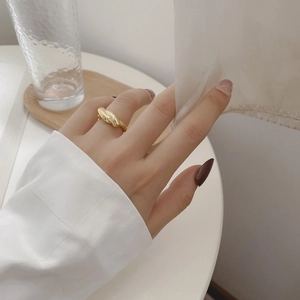Close-up of elegant gold twisted rope ring worn on hand in a minimalist setting