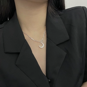 Detail of shimmering 925 silver crescent moon pendant necklace worn on a black blazer