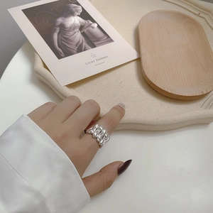 Detailed view of 925 sterling silver braided ring worn on hand with vintage backdrop