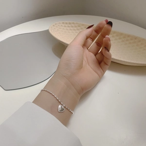 Detail of S925 sterling silver beaded bracelet with heart pendant on wrist