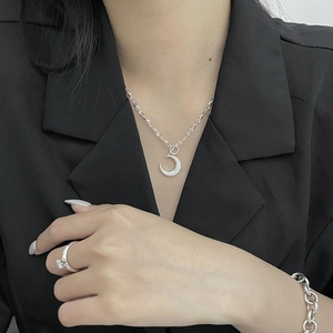Detailed view of silver crescent moon necklace and chunky chain bracelet on a model