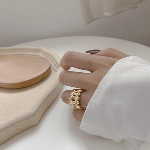Close-up of a gold woven texture ring with a twisted rope design on a model's finger