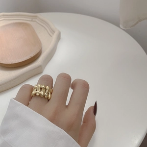 Detail of a gold woven texture ring worn on a finger for a luxurious minimalist look