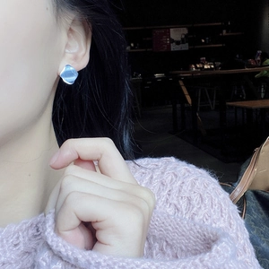 Close-up of minimalist light blue square stud earrings on female model's ear