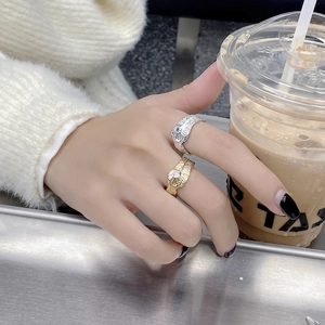 Detailed view of gold and silver plated lava texture rings set with clear zircon stones