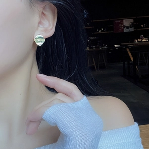 Elegant gold geometric earrings with hammered metal texture worn by a female model