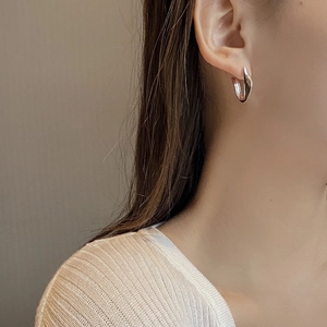 Gros plan d'une boucle d'oreille torsadée en C en argent S925 sur le mannequin