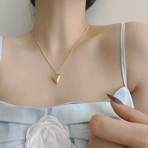 Dettaglio macro della collana con cuore dorato 18K indossata elegantemente sulla clavicola