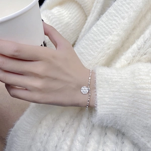 Detail of S925 sterling silver beaded bracelet with hammered lucky round charm on wrist