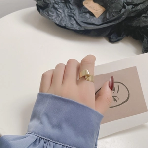 Gros plan d'une bague large dorée torsadée au fini poli miroir sur un doigt de mannequin