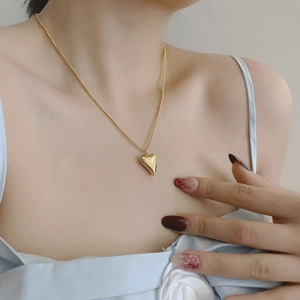 Dettaglio della collana con ciondolo a cuore dorato minimalista indossata con eleganza