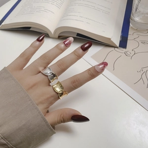 Detailed view of intertwined S925 silver wave rings in gold and silver finish