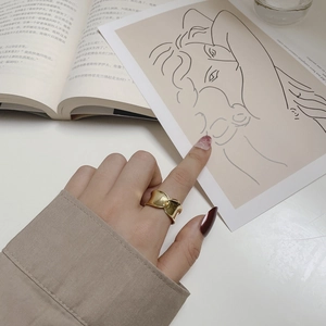 Detailed view of a wide gold-plated twisted knot ring with a fluid metal texture