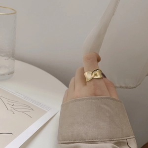 Detail of elegant gold-tone knotted ring worn by a model in a minimalist aesthetic setting