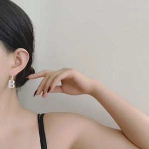 Close-up of minimalist S925 silver letter B pendant earring worn by a model