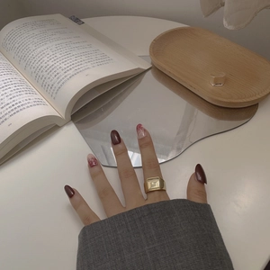 Nahaufnahme breiter goldener quadratischer Ring mit Spiegelglanz auf einem Holztablett