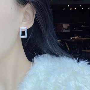 Detail of silver S925 sterling silver rectangular hollow geometric stud earrings on model