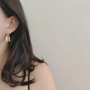 Detailed view of vintage gold letter B earring worn on model for minimalist style