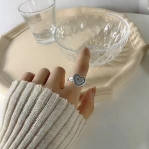 Detail of silver heart-shaped ring with Japanese script on cream ceramic tray