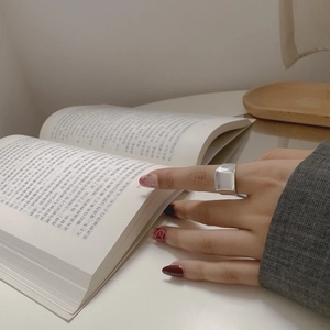 Detail eines minimalistischen S925-Silberrings in Rechteckform beim Lesen