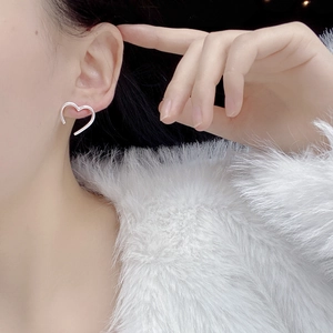 Close-up of minimalist S925 sterling silver hollow heart stud earring worn by a model