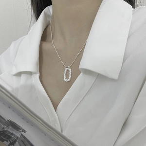 Detail of silver S925 geometric rectangle pendant necklace on white shirt