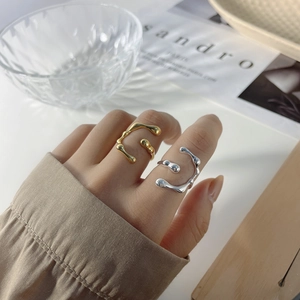 Close-up of gold and silver liquid metal style open rings with lava texture