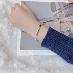 Detail of S925 sterling silver open bangle featuring irregular hammered texture on wrist