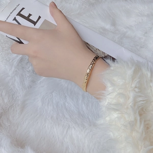 Detailed view of gold irregular hammered texture cuff bracelet on a female wrist