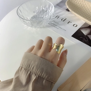 Close-up of a minimalist gold irregular curved ring worn with a stylish outfit