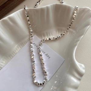 Macro detail of faceted 925 sterling silver beads necklace on a ceramic shell plate