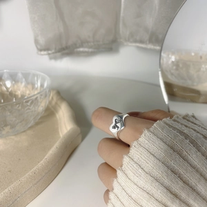 Detail view of silver heart ring with butterfly engraving worn on a finger