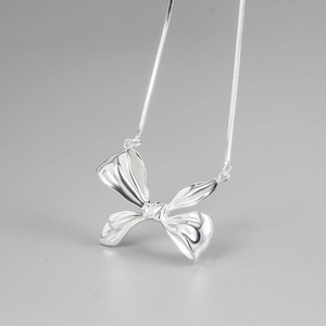 Minimalist S925 sterling silver bow necklace with polished snake chain on grey background