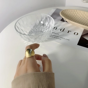 Macro view of wide irregular golden mirror ring showing unique light reflections