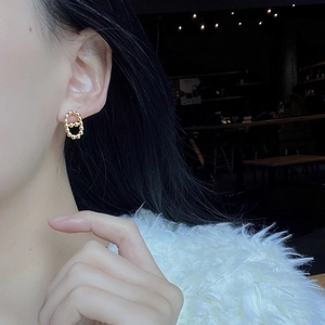Close-up of golden beaded double loop stud earrings worn on ear with high gloss finish