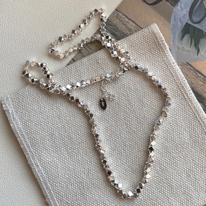 Minimalist 925 sterling silver necklace with geometric diamond-shaped beads on fabric