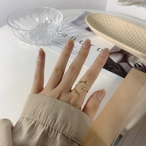 Detailed view of an irregular liquid-style gold-plated open ring on a hand