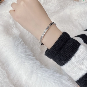 Detailed view of an open silver bracelet with vintage vine textures on a soft plush background