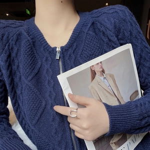 Detail of silver U-shaped open ring styled with a navy blue chunky knit cardigan