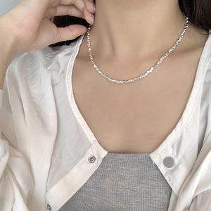 Close-up of faceted 925 sterling silver beads necklace on model with shimmering finish