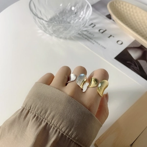 Close-up of irregular 925 silver rings in gold and silver finish with minimalist wave design
