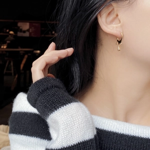 Close-up of golden irregular lava-style stud earrings on model in warm lighting