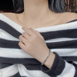 Close-up of S925 sterling silver open bangle with textured bark pattern on model