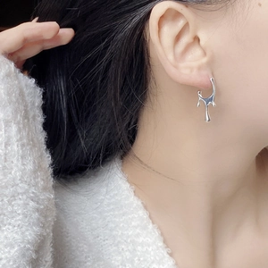 Macro shot of liquid metal style S925 silver stud earrings with smooth fluid texture