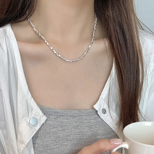 Close-up of a faceted 925 silver beaded necklace worn on neck with minimalist style